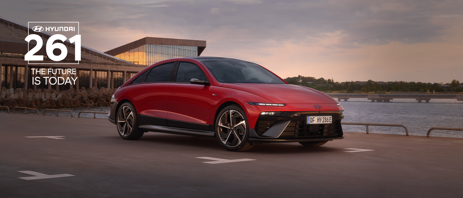 Hyundai IONIQ 6 electric sedan shown from the side parked on a city street with high rise buildings.